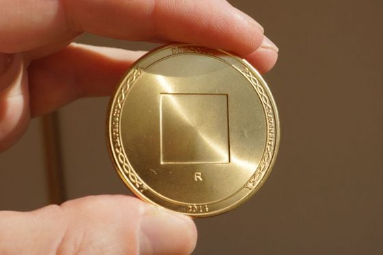 Magnifying glass over bitcoin, cryptocurrency physical coin on