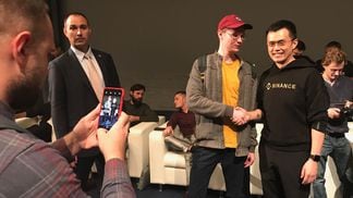 Binance CEO Changpeng "CZ" Zhao shakes hands with an unidentified person, poses for a photo