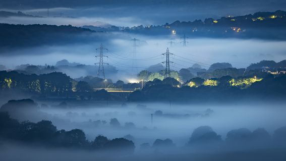 Misty valley in Leeds, Yorkshire with electricity pylons