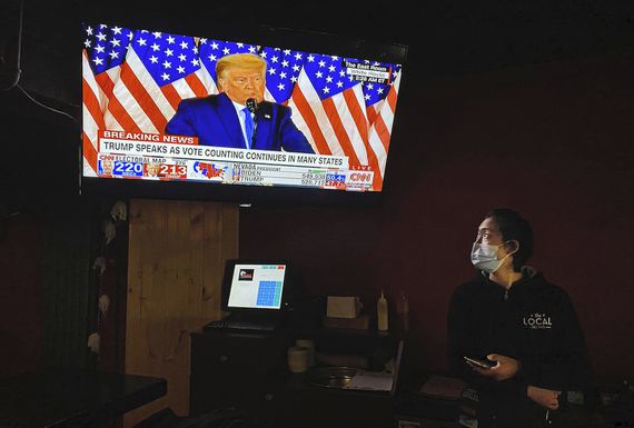 A waitress at a local bar in Beijing watches as U.S. President Donald Trump speaks via television early Wednesday.
