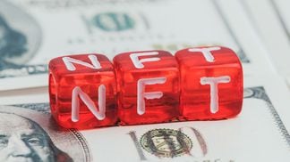 non fungible tokenabbreviated as NFT in white letters on red dice against the background of dollars (Getty Images)