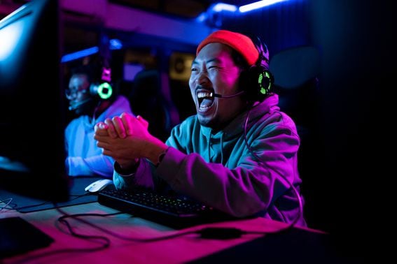 Cheerful Asian gamer celebrating after winning in video game.