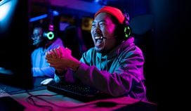 Cheerful Asian gamer celebrating after winning in video game.